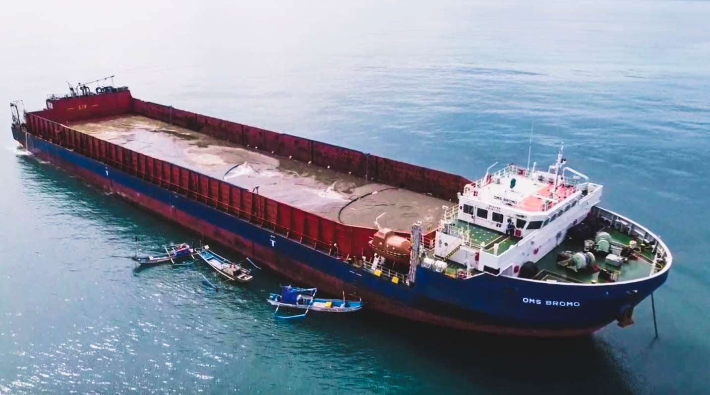 Aerial view of OMS Bromo bulk carrier at sea with small Indonesian support boats alongside